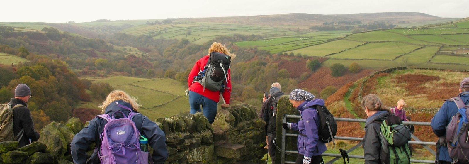 Walkers crossing a stile above Bretton Clough